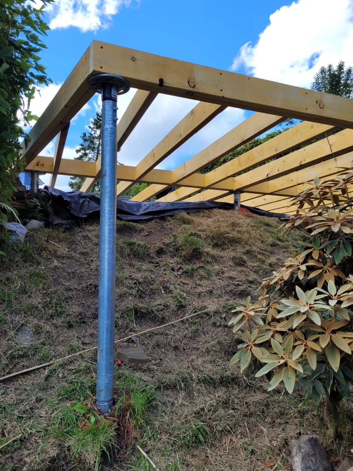 RADIX ground screw installation supporting wooden pergola structure with blue support post visible in landscape setting